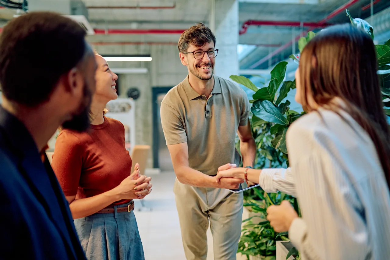 Un espace de bureau ouvert avec de nombreuses personnes travaillant à des bureaux. L'espace est lumineux avec de grandes fenêtres et un mobilier moderne.